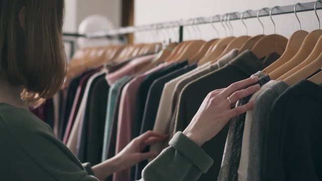 Young woman choosing clothes on rack