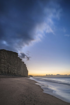 Beautiful vibrant long exposure sunrise landscape image of West Bay in Dorset England