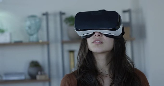 Young hip woman wearing VR 360 goggles in living room - mesmerized by technology