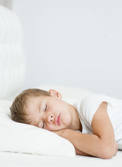 Obraz na płótnie Canvas little boy sleeping on the bed. Space for text