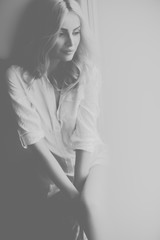 Fototapeta premium Blond woman sitting by window at day light