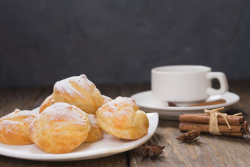Delicious eclairs sprinkled with icing sugar, stand on a wooden table. Copy spase.