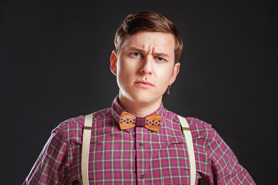 Look at this! Handsome young scientific man in vintage shirt bow tie pointing copy space and smiling while standing against black background. Education Emotios People Business concepts