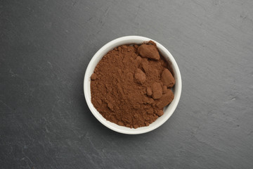 Cacao en polvo en un bol de cerámica blanco sobre un fondo de piedra negra