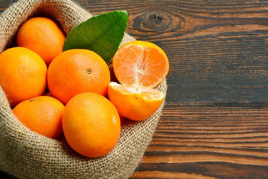 A lot of Clementines,orange or citrus in sack bag on wooden background