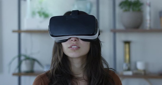 Young hip woman wearing VR 360 goggles in living room - slow motion