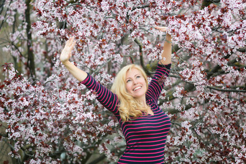 Caucasian blond woman laughing near blossoming tree