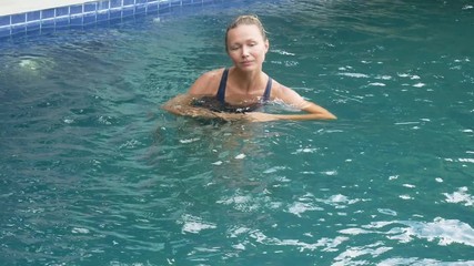 Happy young woman relaxing by the luxury swimming pool