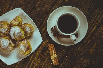 Delicious eclairs sprinkled with icing sugar, stand on a wooden table. Copy spase.