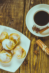 Delicious eclairs sprinkled with icing sugar, stand on a wooden table. Copy spase.
