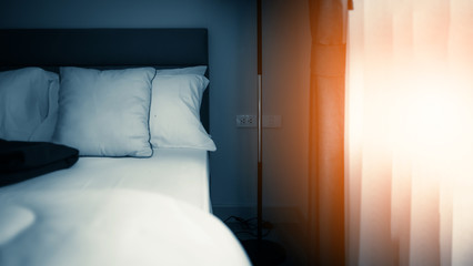 Bed maid-up with clean white  pattern pillows and bed sheets in beauty room. Close-up. Lens flair in sunlight.