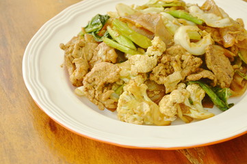 fried large rice noodles with pork and vegetable in black soy sauce on plate