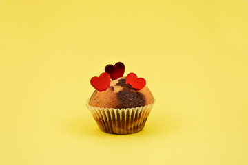 Muffin with hearts stock images. Chocolate muffin with heart on a yellow background. Sweet birthday pastry. Valentines Day concept