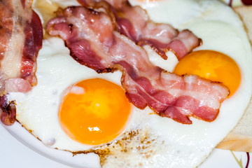 tasty bacon stripes lies on fried eggs