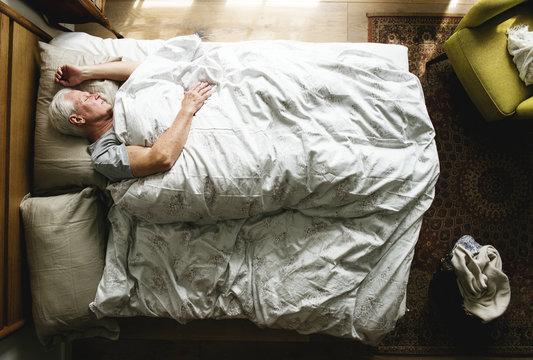 Elderly Caucasian man sleeping on the bed
