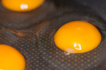 raw eggs lies in a black pan