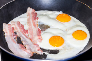 tasty bacon stripes lies on fried eggs