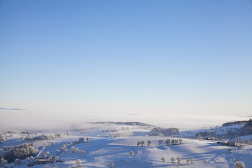 Fototapeta na wymiar snowy hilly winter landscape with foggy sky