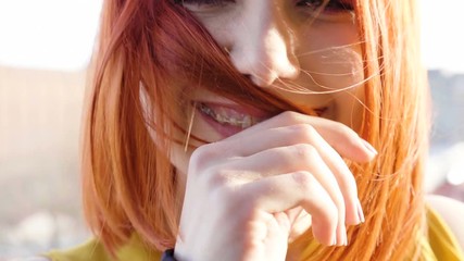 Slow motion of goregous redhead woman smiling at the camera and the wind is blowing her hair