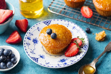 Muffin, cake with fresh berries on a plate. Blue background