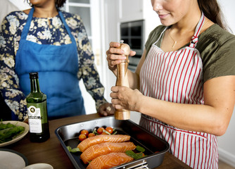 Woman adding spices and herb to raw salmon