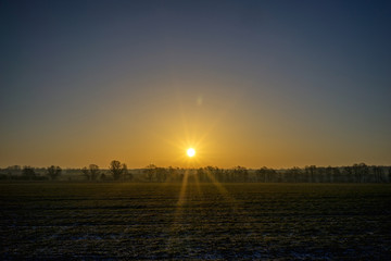 Sonnenaufgang hinter einem Feld