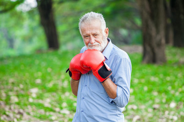 Happy funny senior boxer man with red gloves in park