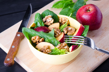 Spinach salad with nuts and apples served on table