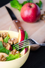 Spinach salad with nuts and apples served on table