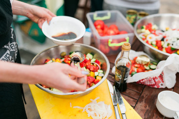 Outdoor salad preparation with juicy, ripe and natural ingredients. Feta, tomatoes, cucumbers, peppers, olive oil and more