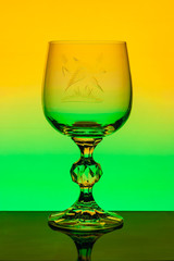 Crystal wine glass with engraved pattern  on a background of multi colored gradient