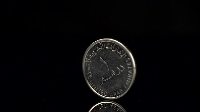 United Arab Emirates dirham spining over black background. Slow motion shot. 

