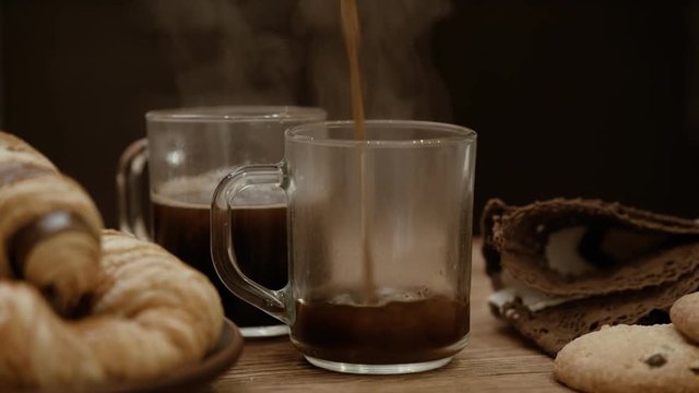 Pouring coffee into cup .  Steam from a cups with a hot coffee .  Breakfast.