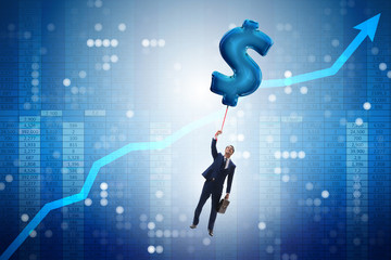 Businessman flying on dollar sign inflatable balloon