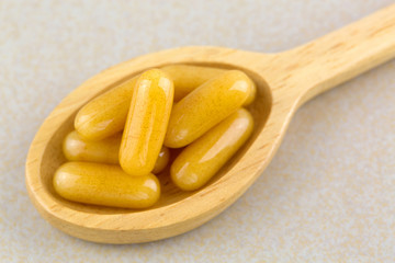 Closeup concentrated Royal Jelly in soft gel capsules in wooden spoon
