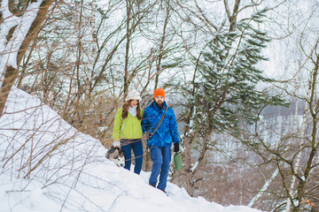 Woman and man are having walk with dog in winter snowy countryside. Happiness, winter holidays, tourism, travel and people concept.