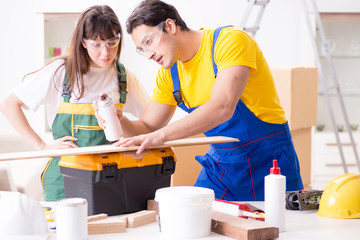 Man explaining woman woodworking tips in wood workshop