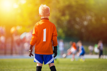 Young Soccer Goalie Goalkeeper. Young Boy Soccer Goalie. Soccer Game on Sunny Summer Day. Sport activities for children.. Football Match in the Background. Youth Sport Wallpaper.