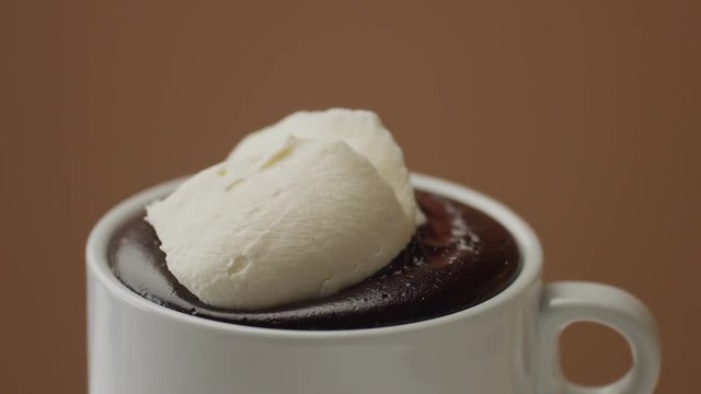 closeup of cream on hot choaolate. spoon with a cream putting in on hot chocolate