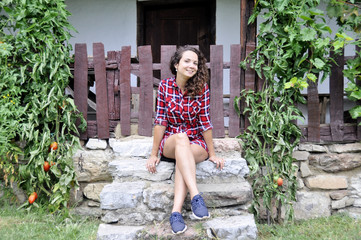 young girl sitting on the steps of an old rural house.