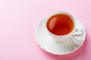 Tea in white cup on pink background. Copy space.