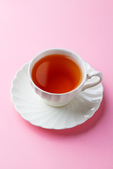 Tea in white cup on pink background. Copy space.