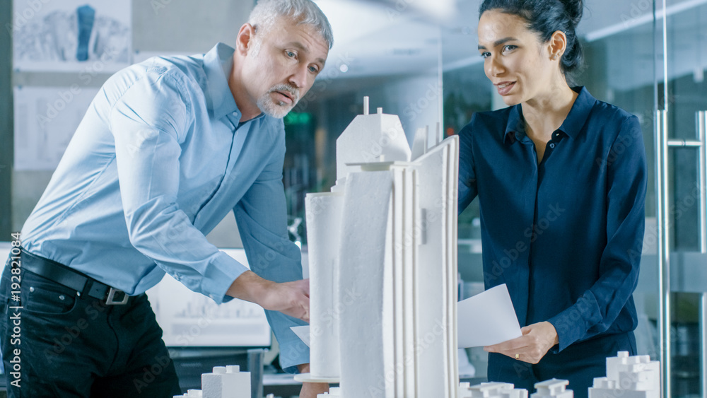 Aufkleber in the architectural bureau twoprofessional engineers work on a model of a city district. urban plan