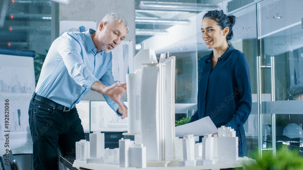 Aufkleber two professional male and female architectural engineers work with blueprints and on a building mode