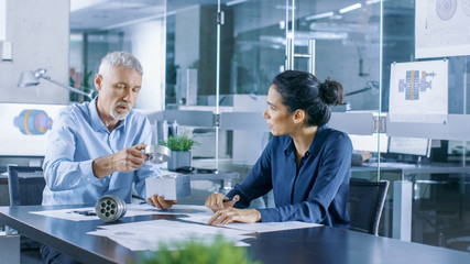 Experienced Male and Female Industrial Engineers have Discussion, Making Adjustment and Perfecting Parts, They Work on a Machinery Component Design. They Office is Stylish and Modern Looking.