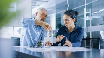 Experienced Male and Female Industrial Engineers have Discussion, Making Adjustment and Perfecting Parts, They Work on a Machinery Component Design. They Office is Stylish and Modern Looking.