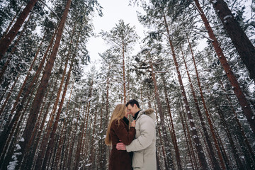 Loving couple in a pine forest in winter