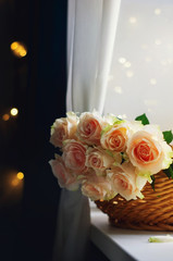 Bouquet of pale pink cream roses in a woven basket on a windowsill. Soft focus. Romance background with copy space.