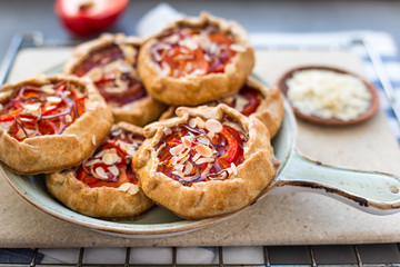 Mini pizza, vegetable galette with cream cheese, red onion, tomatoes, sweet pepper and almonds
