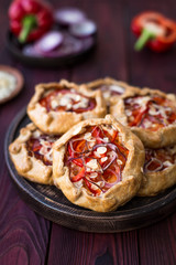 Mini pizza, vegetable galette with cream cheese, red onion, tomatoes, sweet pepper and almonds